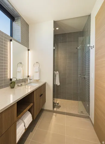 Modern bathroom featuring a glass-enclosed shower with horizontal tile surround and a tiled floor