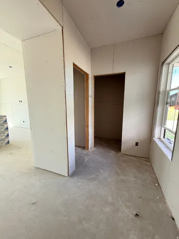 Unfinished interior space featuring drywall installation, two open doorways, and an exposed concrete floor