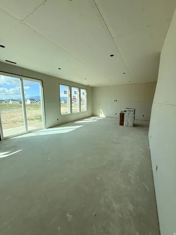 Expansive open-concept room with multiple windows, a sliding glass door, and recessed ceiling lighting