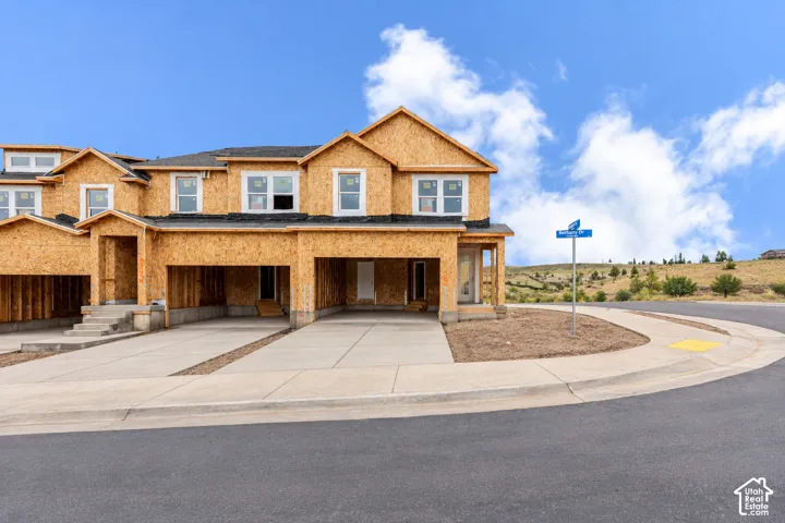 Multi-unit exterior featuring oriented strand board sheathing, multi-gabled rooflines, double-car garages, and concrete driveways