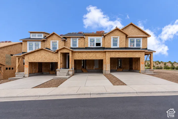 Multi-unit residential structure featuring wood-sheathed exterior, concrete driveways, and multiple garage bays