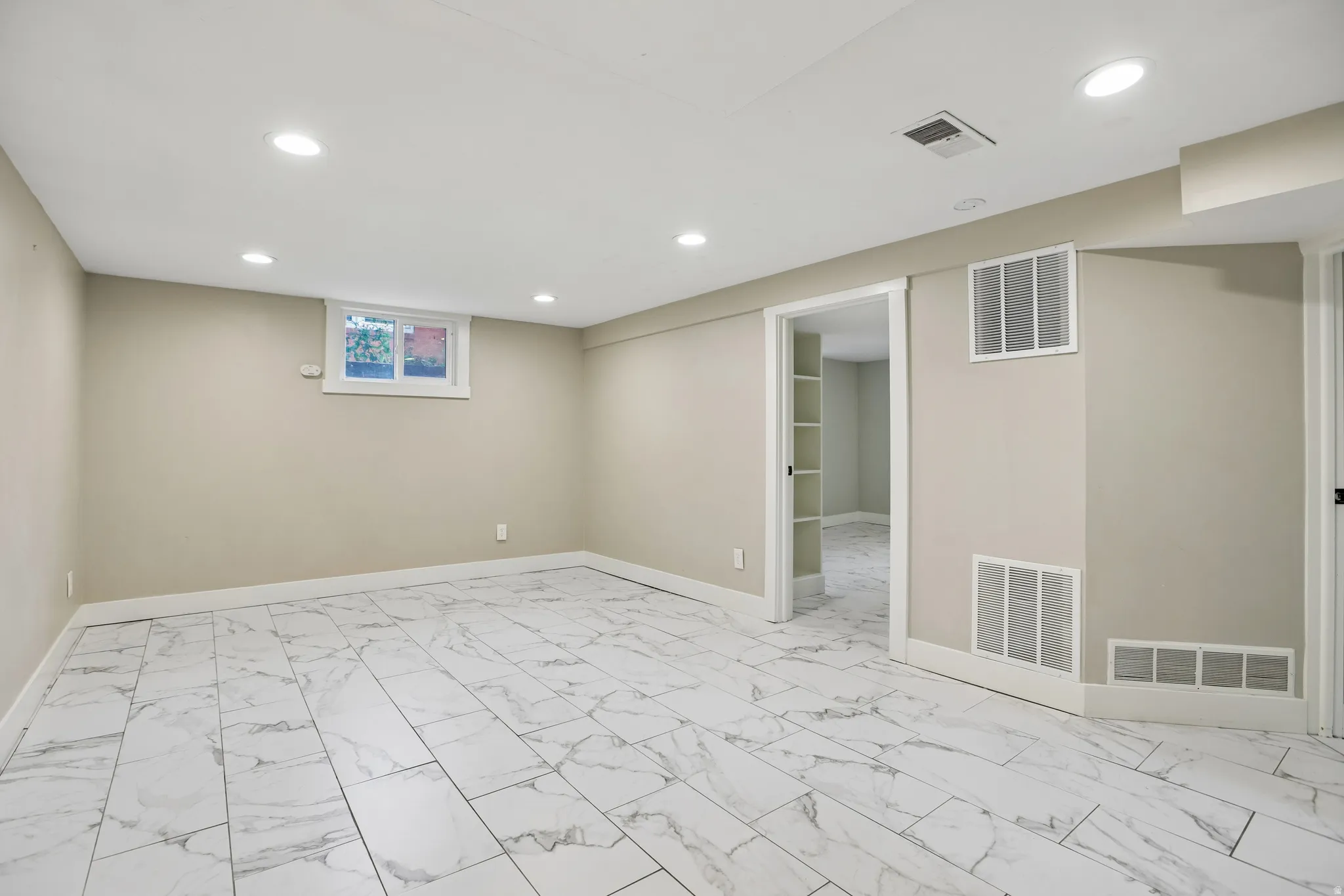 Recessed lighting, light-toned wall paint, white trim, window, and large format tile flooring