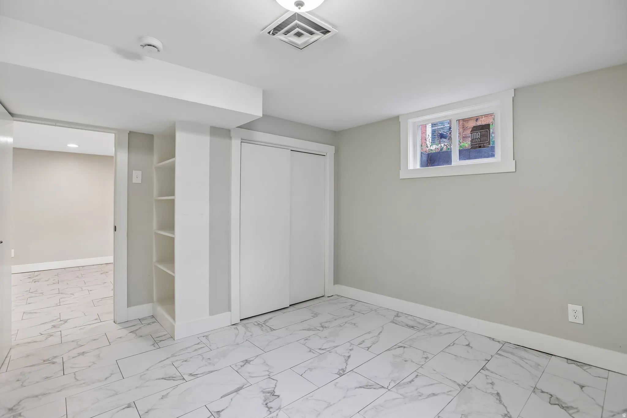 Light gray wall paint, white trim, recessed lighting, built-in shelving, and large format tile flooring