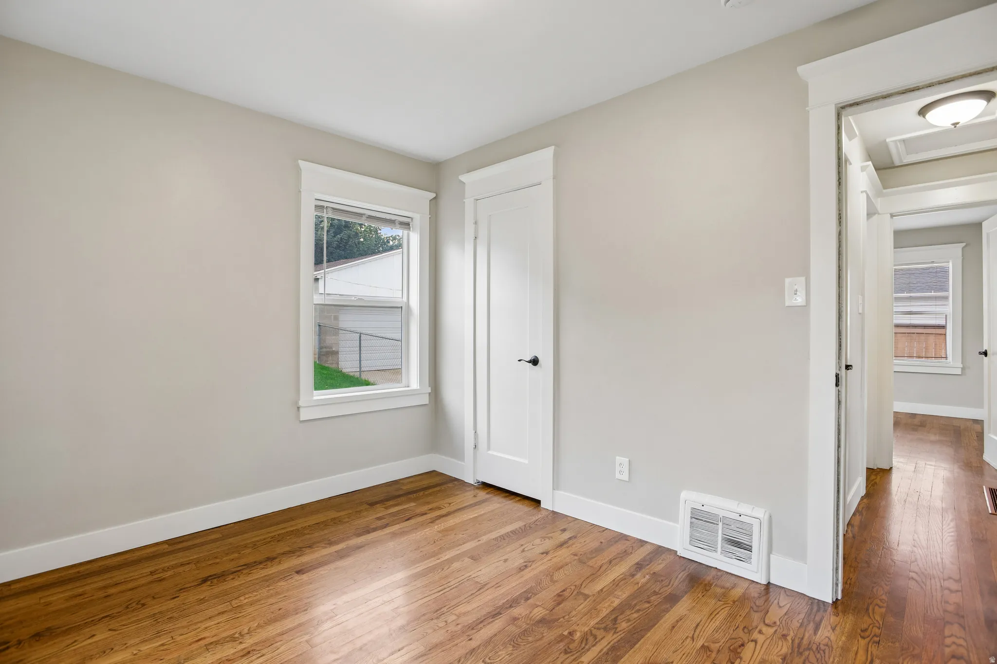 Hardwood flooring, painted walls, white trim, white interior doors with black hardware, and a single window