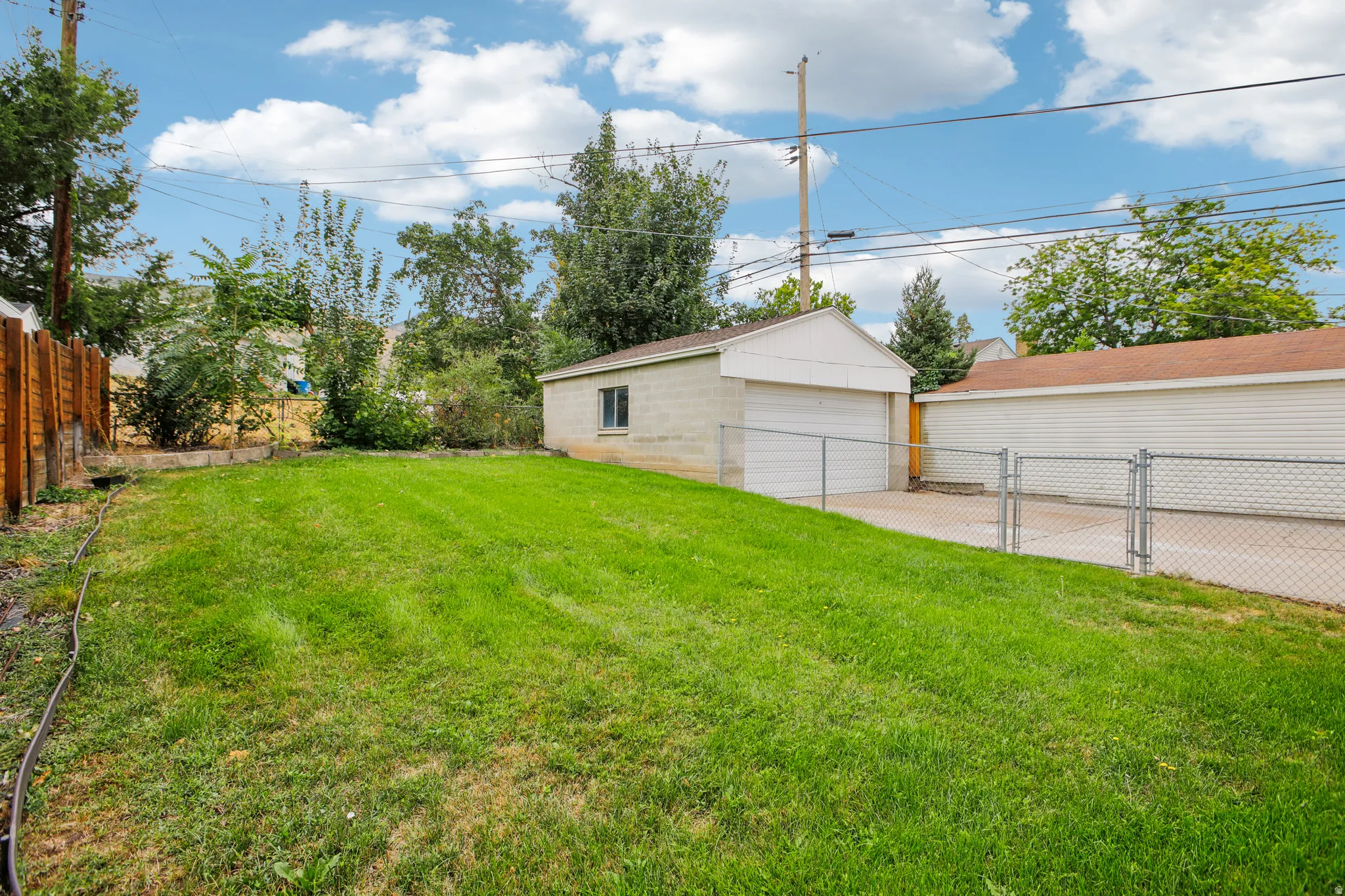 Expansive lawn area with a wood fence, concrete driveway, and a detached two-car garage