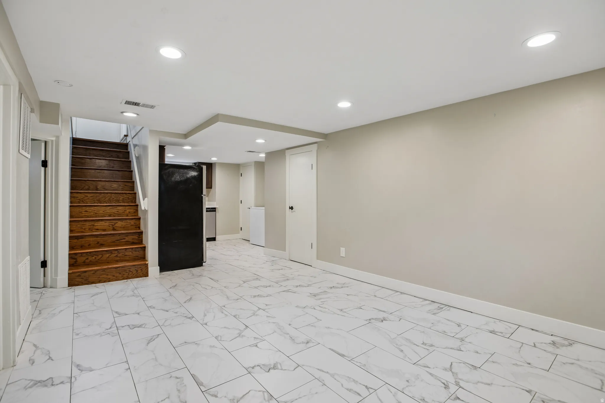 Recessed lighting, wood staircase, white tile flooring, neutral wall tones, and white trim