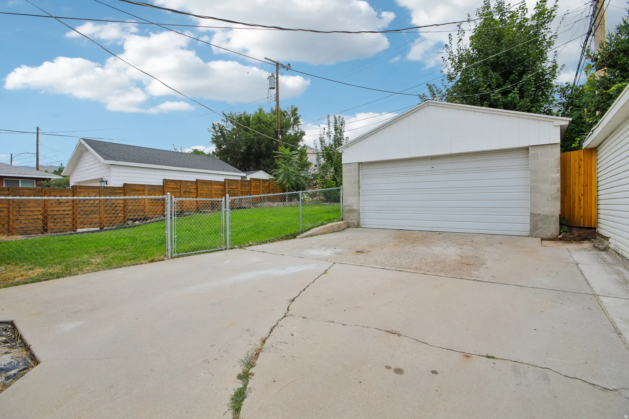 Detached two-car garage with a roll-up door, concrete block foundation, and concrete driveway