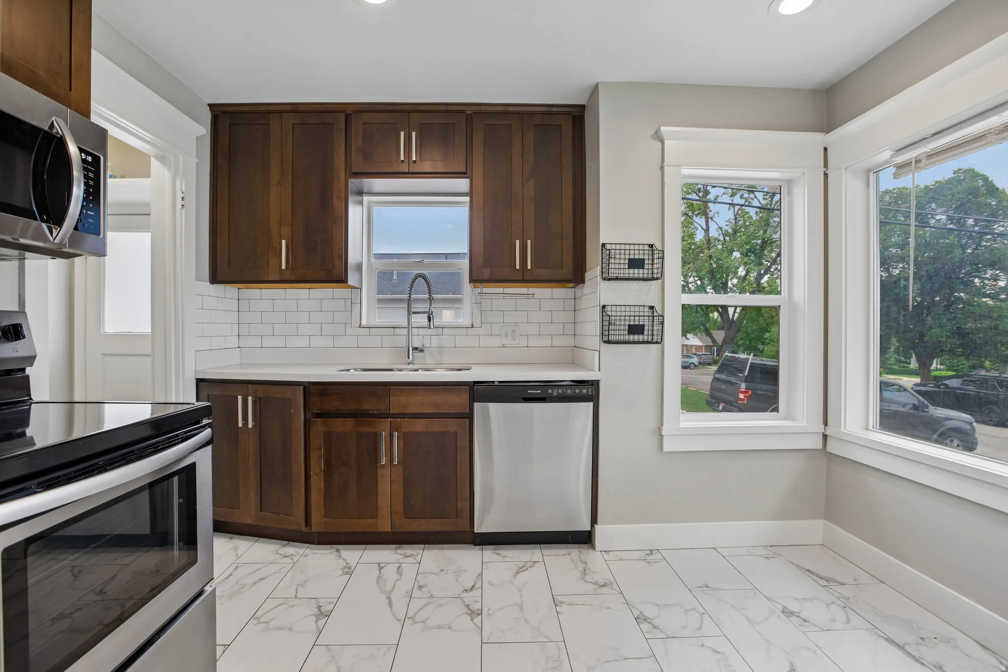 Kitchen featuring wood cabinetry, stainless steel appliances, white subway tile backsplash, white countertops, and white tile flooring