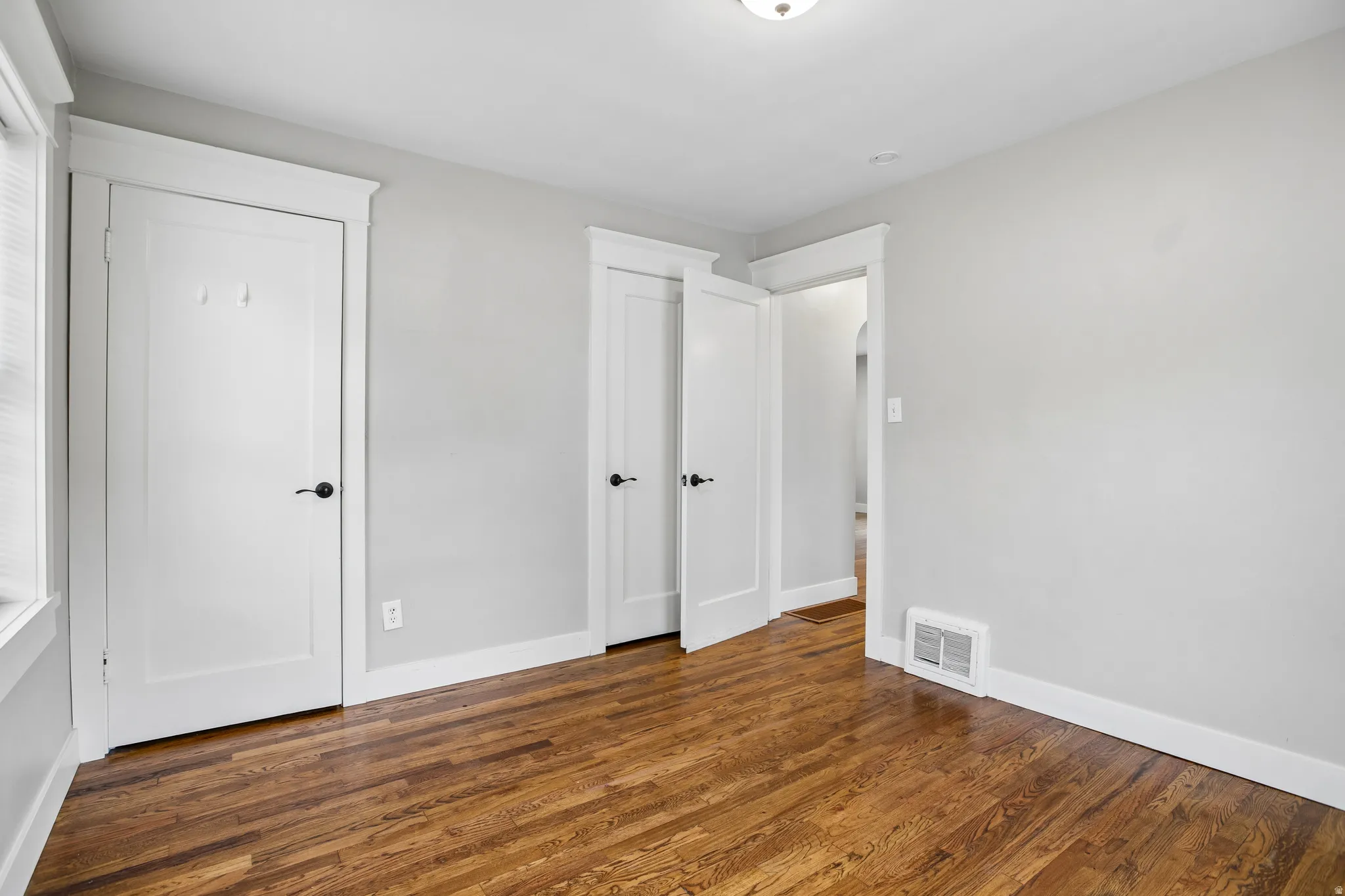 Hardwood flooring, painted walls, white trim, white doors, and a ceiling light fixture
