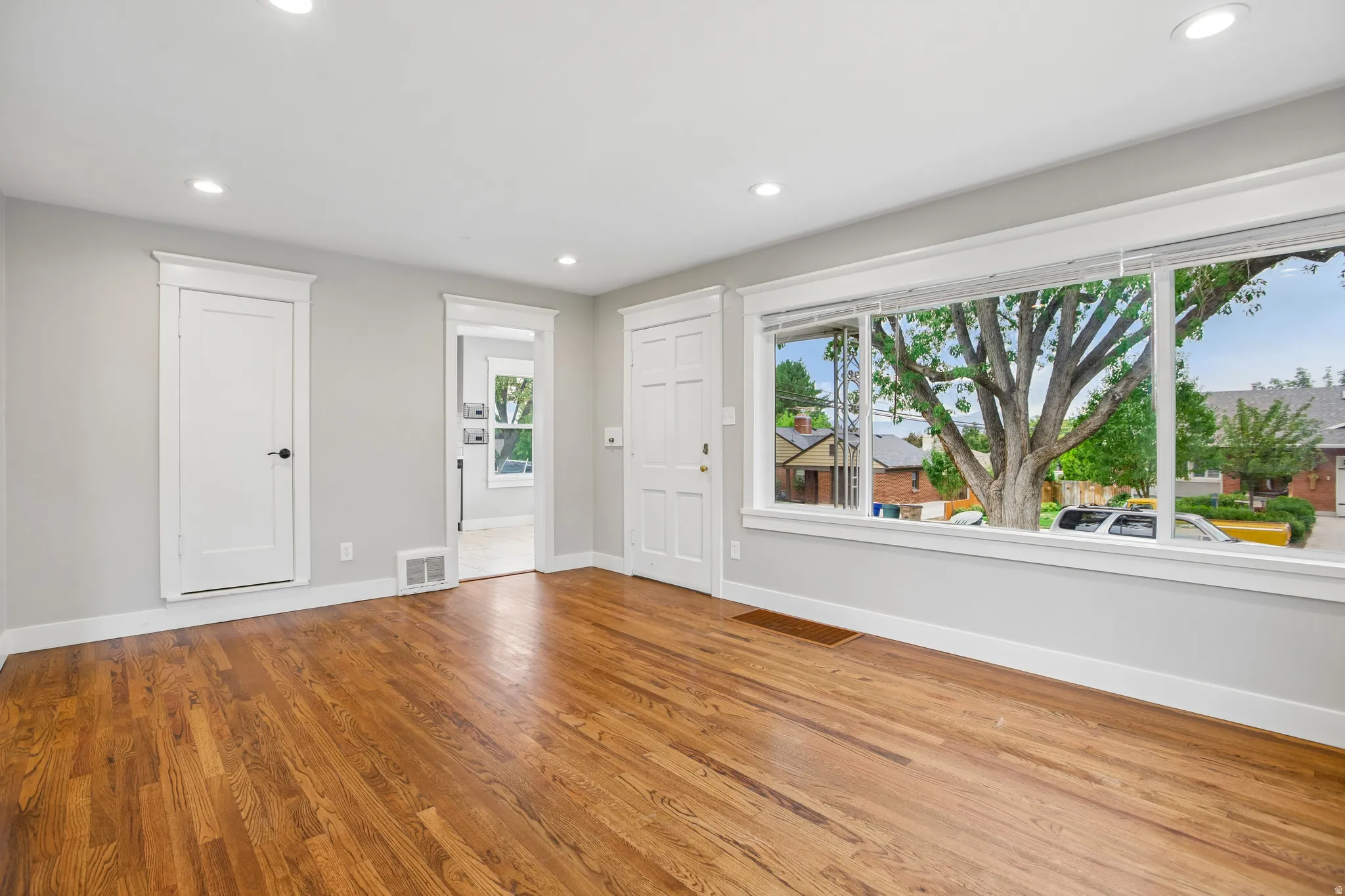 Hardwood flooring, recessed lighting, expansive picture window, and white trim work