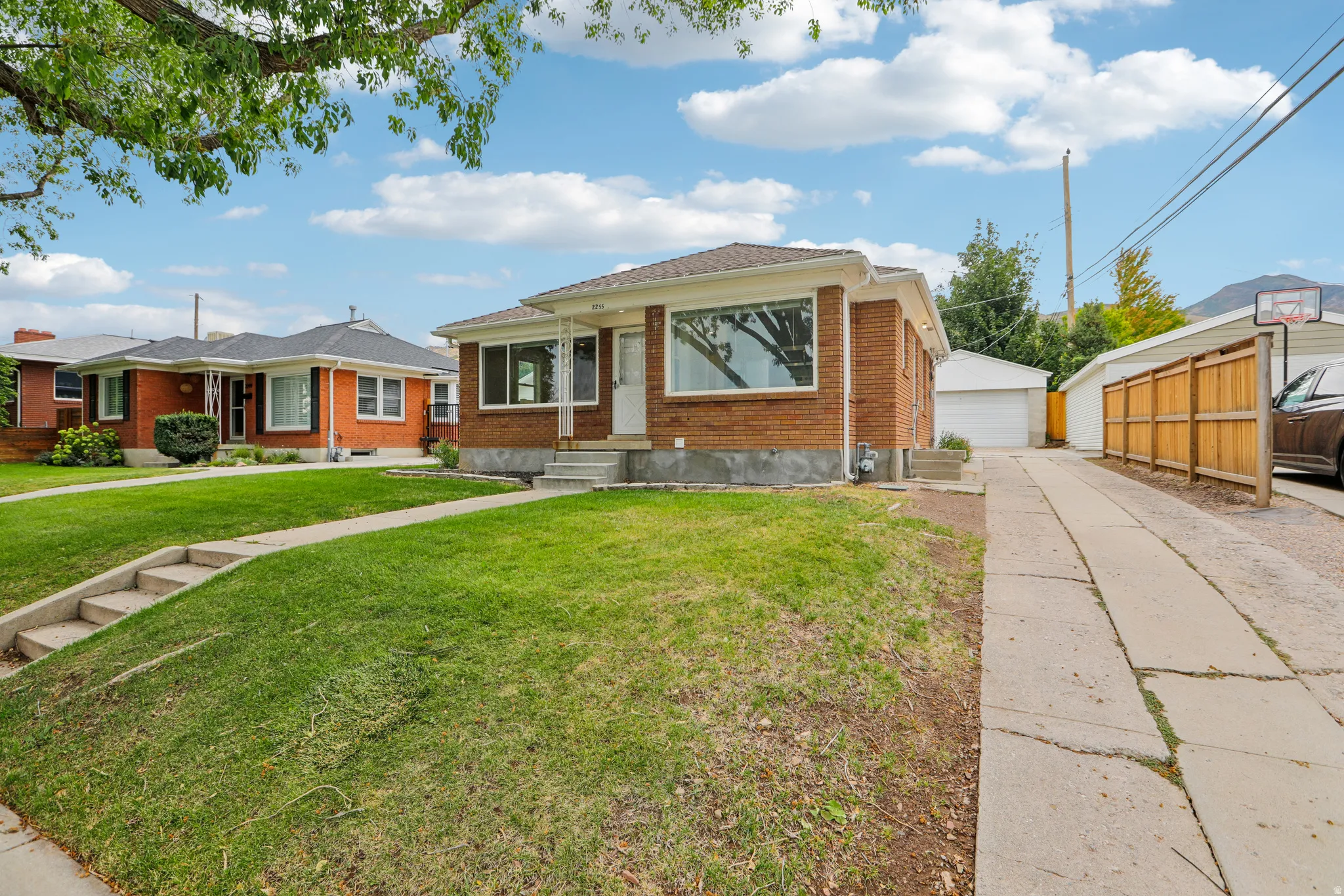 Brick exterior with expansive front lawn, concrete walkway, and detached garage