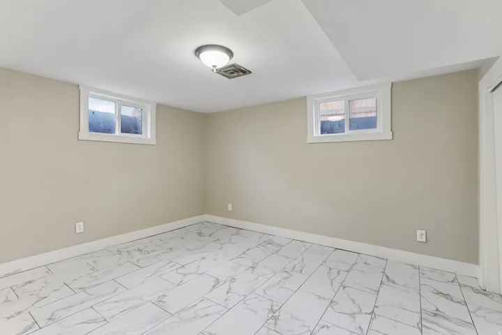 Recessed lighting with a flush-mount fixture, two framed windows, light-toned wall paint, and marble-patterned tile flooring