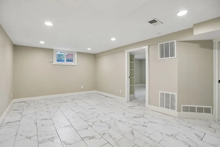 Recessed lighting, light-toned wall paint, white trim, window, and large format tile flooring