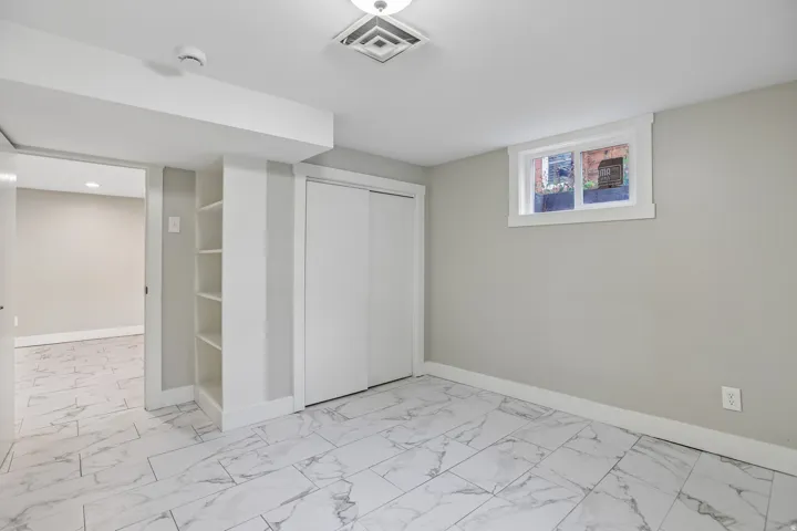 Light gray wall paint, white trim, recessed lighting, built-in shelving, and large format tile flooring