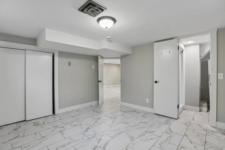 White marble-look tile flooring, light gray walls, white trim, sliding closet doors, and recessed ceiling lighting