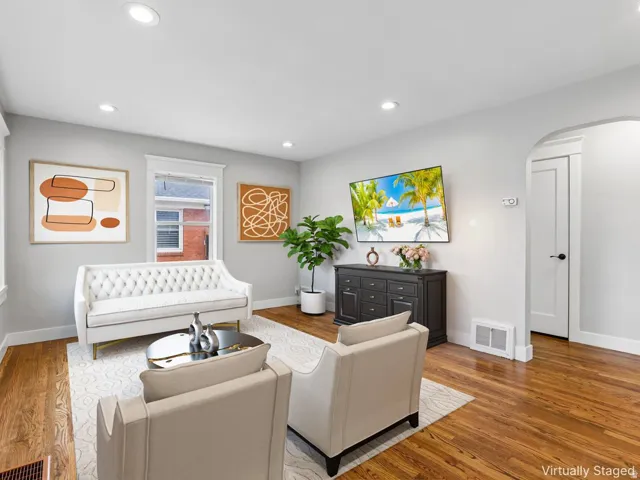 Hardwood flooring, recessed ceiling lighting, arched doorway, white trim, and a built-in wall vent