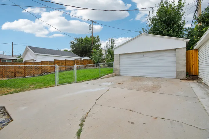 Detached two-car garage with a roll-up door, concrete block foundation, and concrete driveway