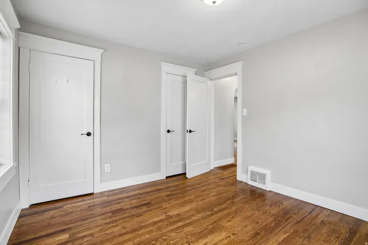 Hardwood flooring, painted walls, white trim, white doors, and a ceiling light fixture