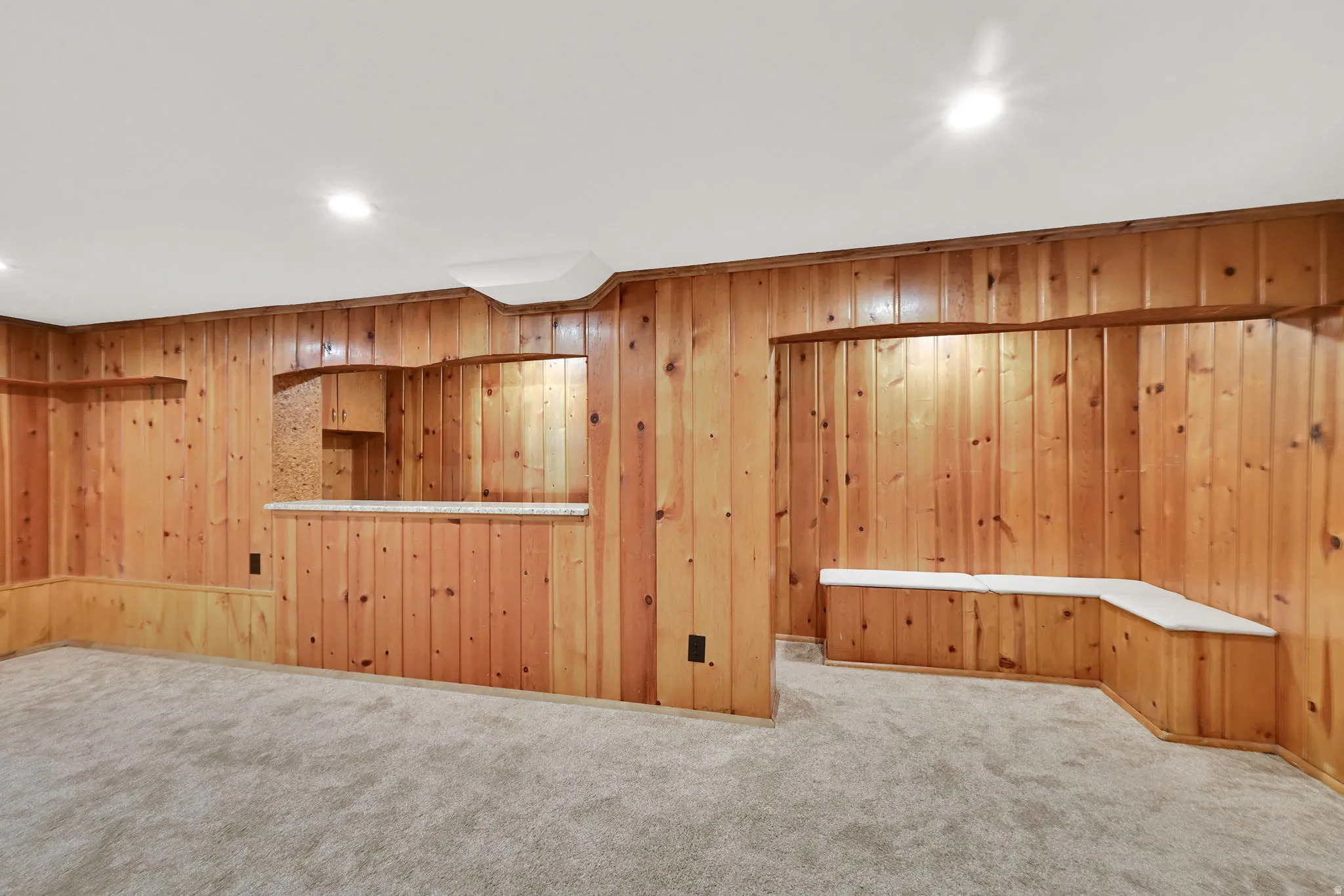 Featuring granite countertops, the dry bar area includes built-in storage seating and rough-in plumbing for a future sink.