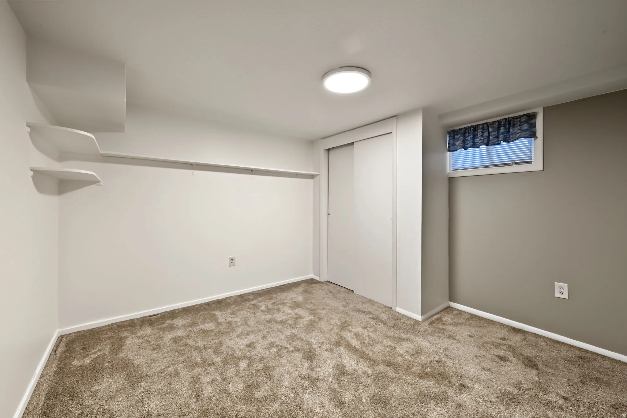 Bedroom three with a built-in closet with sliding doors and neutral paint and carpeting