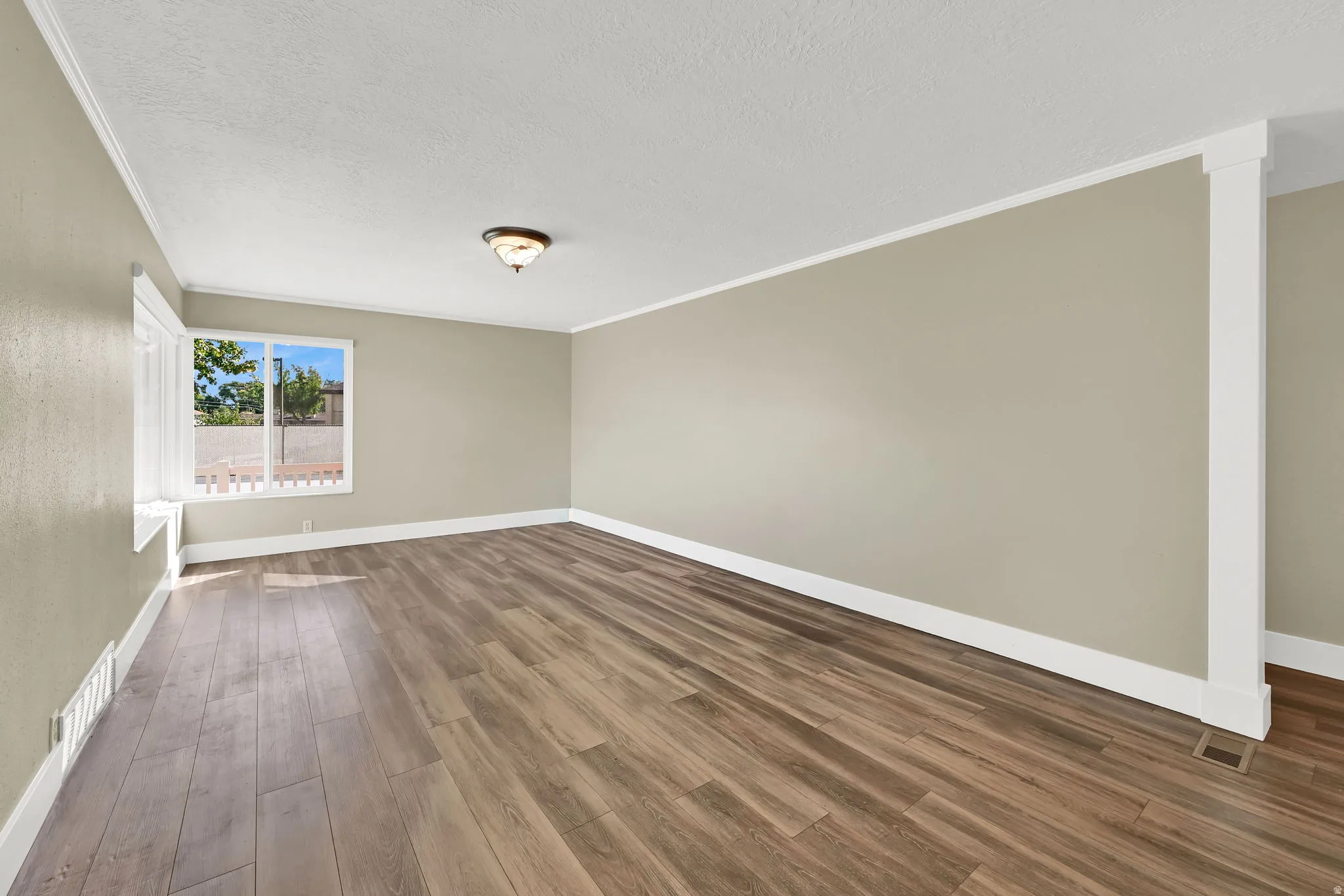 The modern living/family room features warm wood laminate floors and neutral walls that create a bright, open space