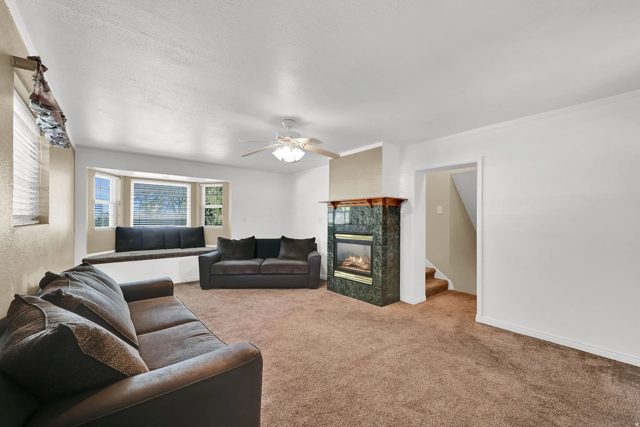 The highlight of this extra family room is a cozy gas fireplace with a wrap-around mantel perfect for seasonal decor, complemented by a charming bay window that offers a comfortable window seat and practical storage below.