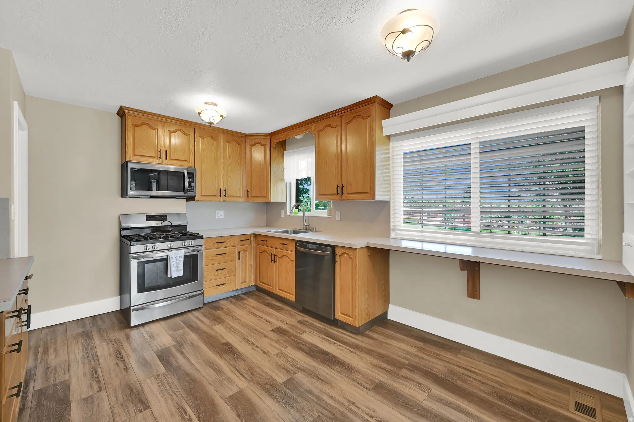 Cook with ease in the updated kitchen featuring a full backsplash, inviting breakfast bar, and natural light. Plumbed/wired for gas or electric range