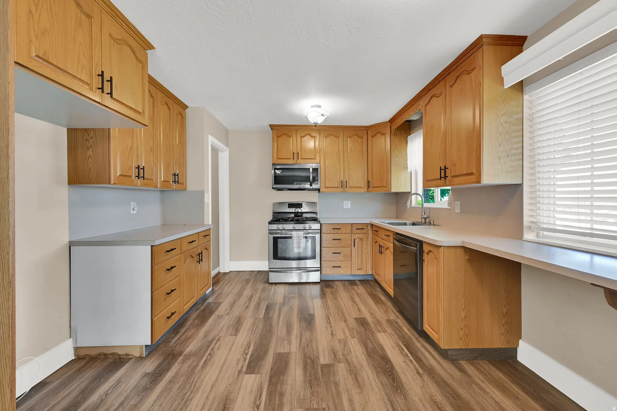 Light wood cabinets are beautifully offset by dark wood laminate flooring. Gas range, microwave and dishwasher are included