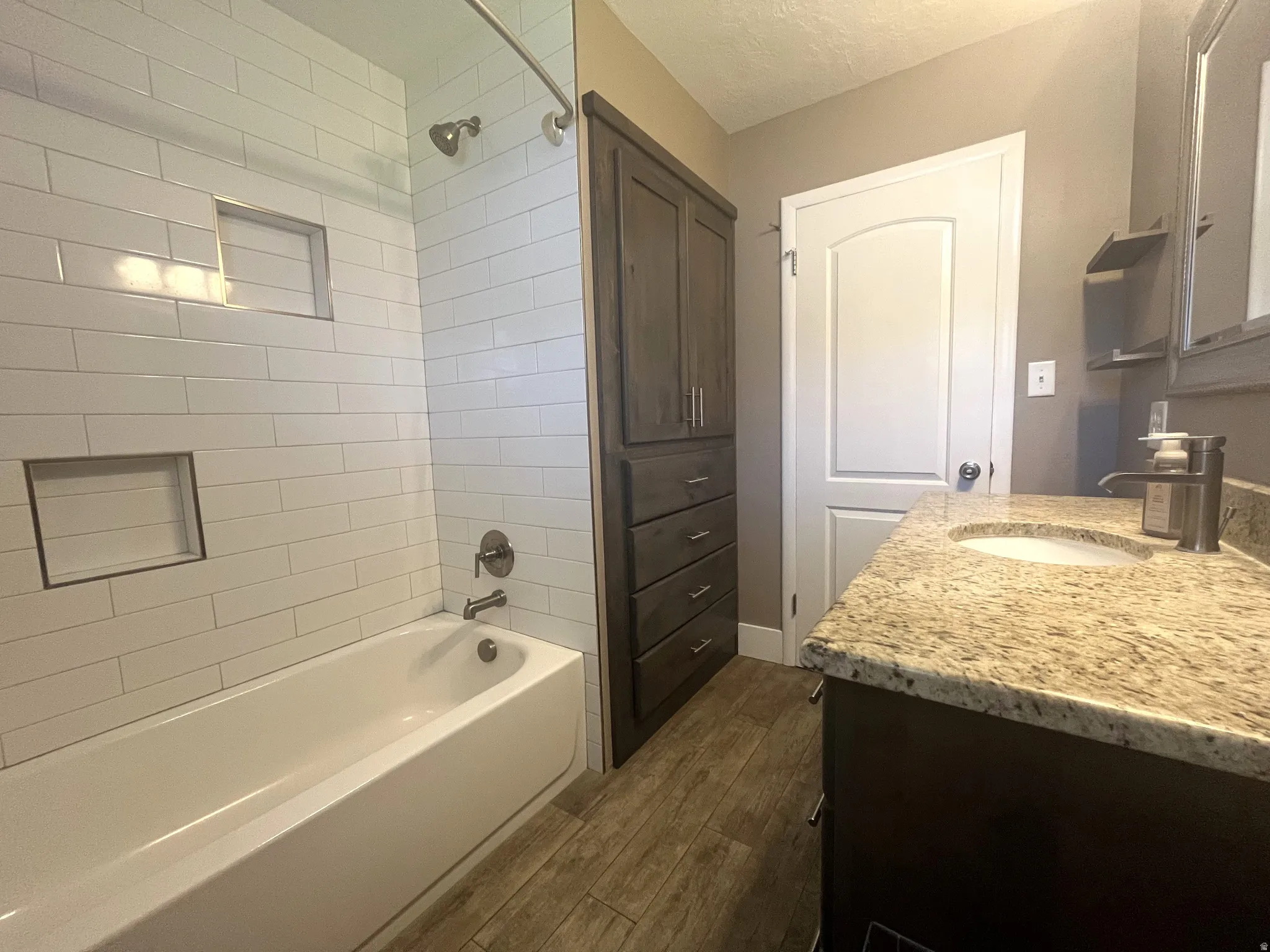 A subway-tile tub/shower combo with integrated niches elevates the space, while custom built-in cabinetry seamlessly stores your beauty supplies and essentials.