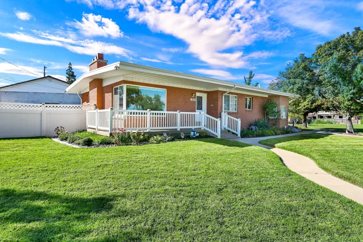 Brick exterior with white trim, featuring a front porch with white railings, a concrete walkway, and a manicured lawn