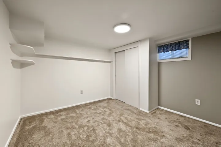 Bedroom three with a built-in closet with sliding doors and neutral paint and carpeting
