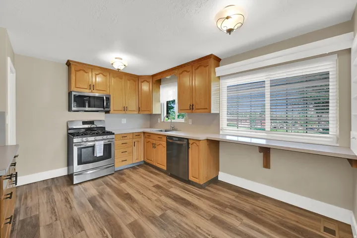 Cook with ease in the updated kitchen featuring a full backsplash, inviting breakfast bar, and natural light. Plumbed/wired for gas or electric range