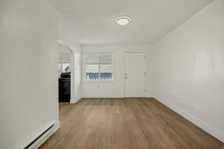 Wood-finish flooring throughout, white baseboards, and a white ceiling with a flush-mount light fixture