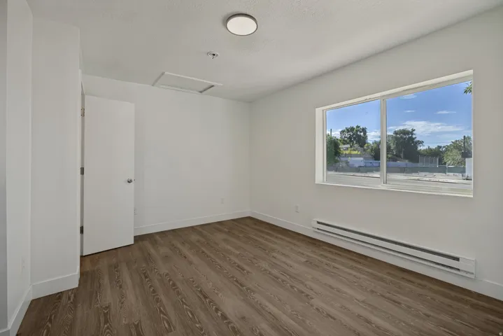Wood-finish flooring, white walls, and a large window