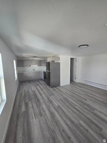 Open-concept living space featuring wood-finish flooring throughout, stainless steel appliances, and gray cabinetry with ample counter space