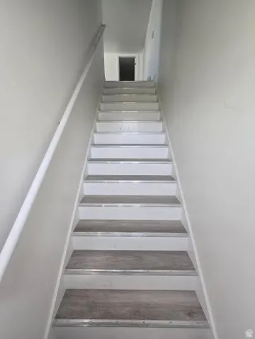 Staircase featuring wood-finish treads and white risers with aluminum trim