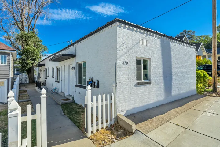 White painted brick exterior with multiple entryways, white picket fencing, and concrete pathways