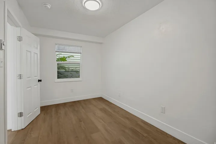 Bright, light-filled bedroom featuring hardwood flooring, recessed ceiling lighting, and a large window with natural light