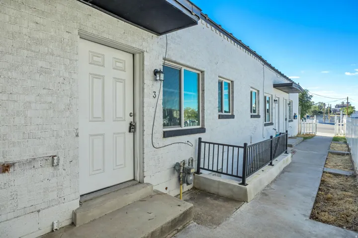 White painted brick exterior with multiple windows and a concrete walkway