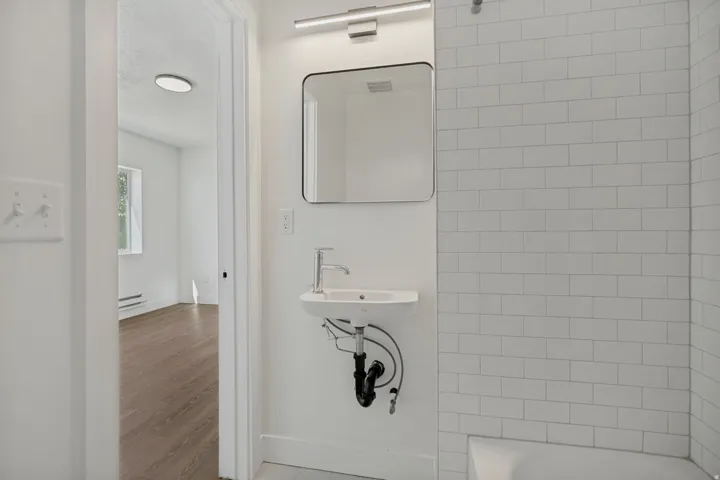 Pedestal sink with chrome faucet, framed mirror, and horizontal vanity light