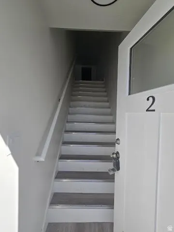 Stairway featuring wood-finish treads with metallic risers and a white handrail
