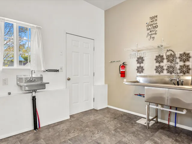 Dual stainless steel utility sinks, window with outdoor light, durable flooring, and a solid interior door