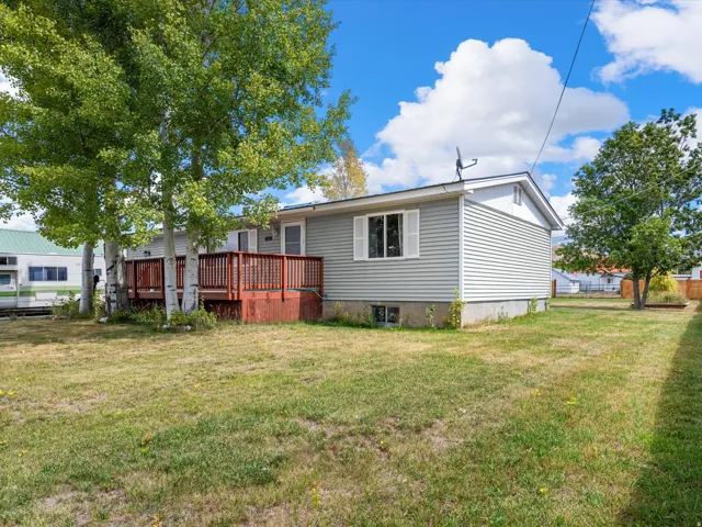 Exterior featuring light gray siding, white window trim, and a red-stained wood deck