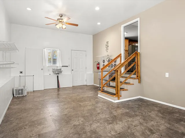 Vinyl plank flooring, recessed lighting, ceiling fan, utility sink, wood staircase