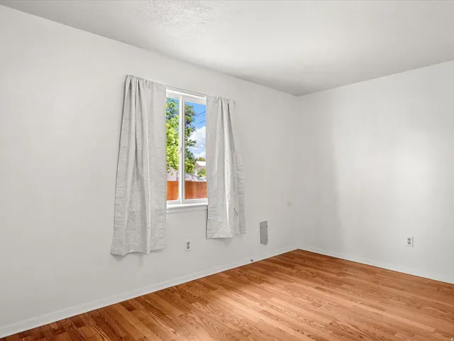 Wood-finish flooring with white walls and a white-framed window