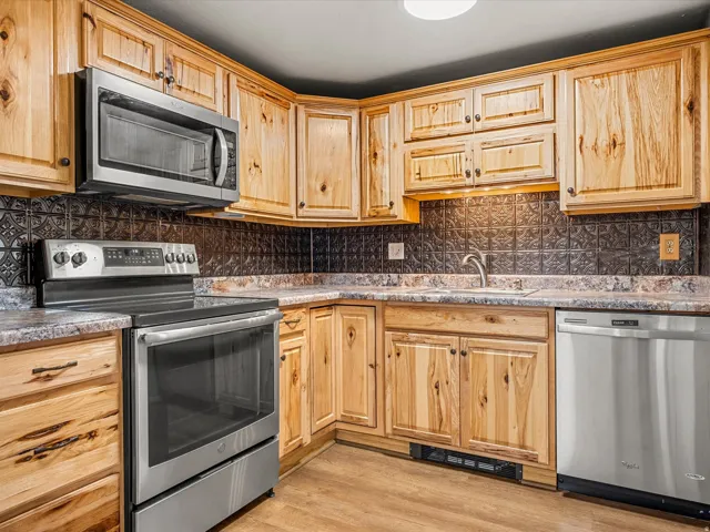 Wood-finish cabinetry paired with a black tiled backsplash