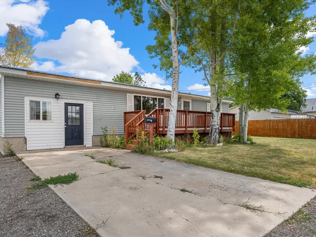 Vinyl siding exterior with a wood deck, concrete driveway, and established trees