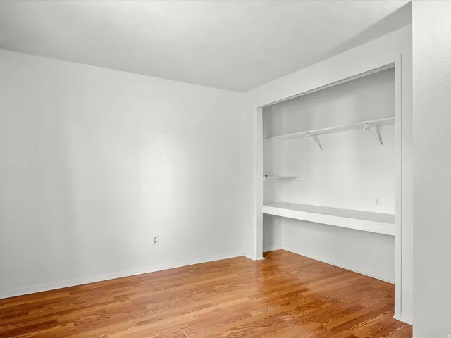 Built-in shelving unit with multiple shelves, wood-finish flooring, and light-toned walls