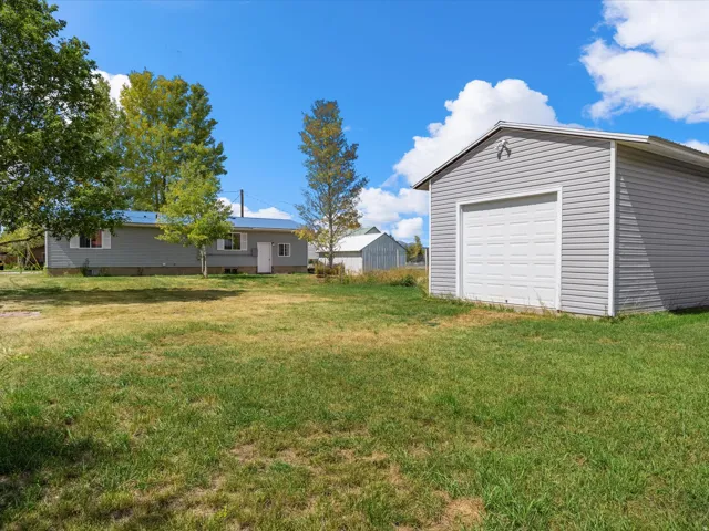 Detached garage with a white overhead door and gray siding