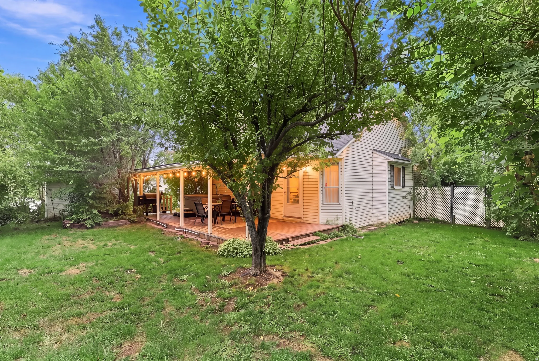 Expansive rear yard featuring mature trees, a covered patio with a solid roof, a privacy fence, and siding exterior